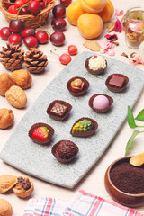 Chocolate candies of different shapes on gray slate plate 
