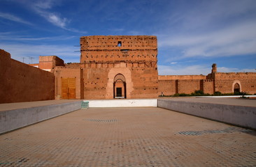 Piękny fragment arabskiego pałacu, w ruinie, tradycyjne dekoracje w style arabskim, przed kamienną ścianą basen bez wody, w tle mur - część kompleksu pałacowego, błękitne niebo