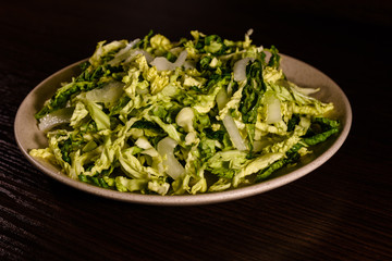 Salad with the savoy cabbage in the dish on dark wooden table