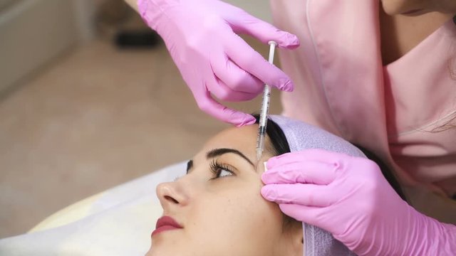 The doctor cosmetologist makes the Botulinum Toxin injection. Procedure for tightening and smoothing wrinkles. Rejuvenating facial injections.