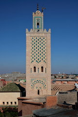 Bogato dekorowany minaret meczetu ponad dachami miasta, słoneczny dzień, błękitne niebo