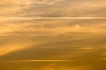 trail from the plane in the sky at sunset