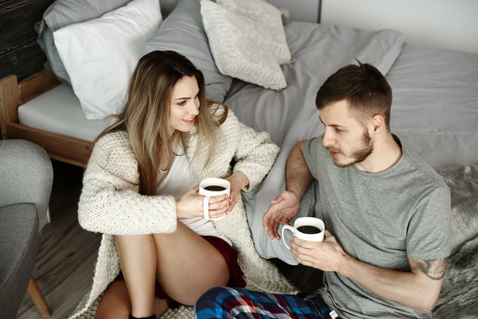 Couple with coffee sitting on floor and talking