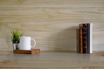 Mockup background, books and coffee mug on wood desk and wooden wall with copy space.