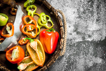 chopped sweet pepper in a wooden tray with a knife.