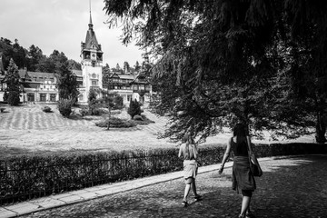 Two young girls passing in front of the famous Peles Palace in Romania, shot in black and white