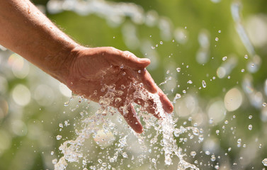 Fototapeta premium Hand of a man in a spray of water from a fountain