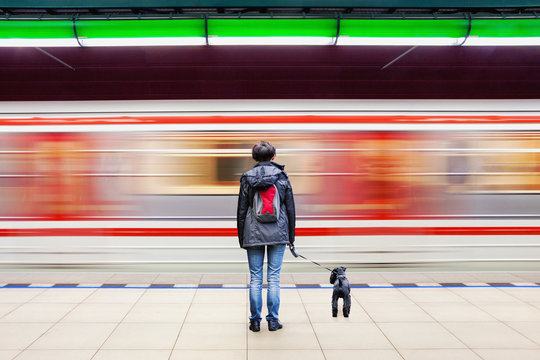 Lonely Woman With Dog At Subway Station Platform With Blurry Moving Train In Background