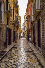 Fototapeta na wymiar Old medieval street and pavement wet from rain in the Italian city of Bari