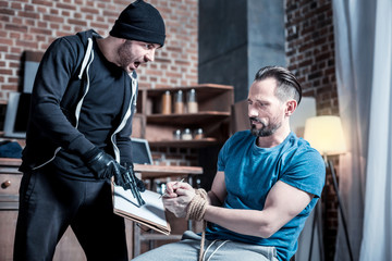 Signing a contract. Shouting cruel bearded criminal crying at a frightened muscular man and making...
