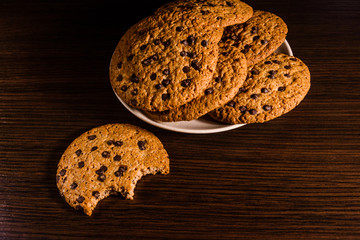 Plate with chocolate chip cookies on a dark wooden table