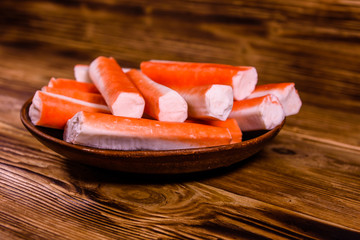 Ceramic plate with crab sticks on wooden table