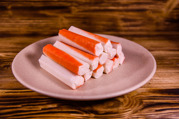 Ceramic plate with crab sticks on wooden table