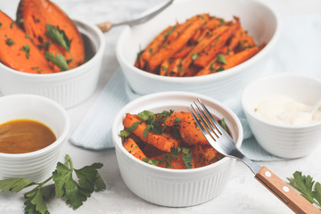Different types of baked sweet potato with curry and a creamy garlic sauce. White dishes, light background. Healthy vegan food concept.