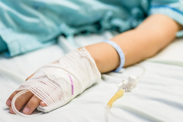 Fototapeta na wymiar Closeup kid hand sleeps on a bed in hospital with saline intravenous.