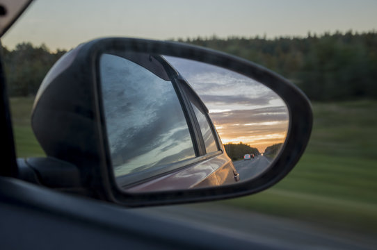 Rear window of auto with view of sundown landscape