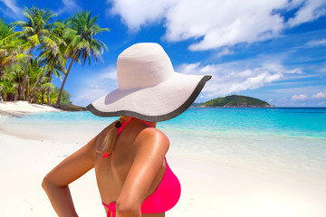 Fototapeta na wymiar Beautiful woman in white hat on the tropical beach