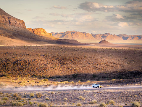 White Pick-Up leaving a trace of dust in the arid mountains of south Namibia