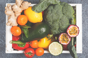 Fresh fruits and vegetables in a white wooden box. A healthy vegetarian farm food concept. Top view