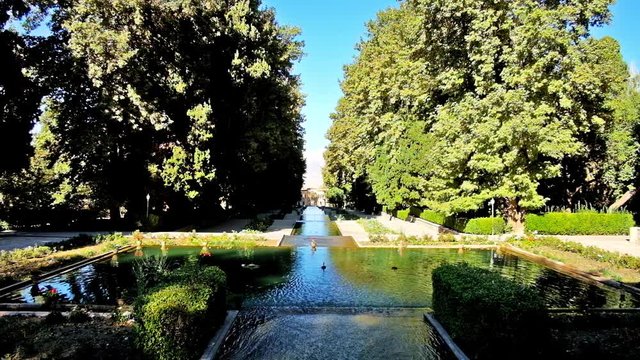 The upper level of historic Shazdeh (Prince's) Garden with lush shady trees and footpathes around the fountain, it's fine example of traditional Persian gardens, Mahan, Kerman, Iran.