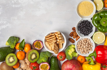 Healthy vegan food concept. Fresh vegetables, exotic and seasonal fruits, tofu, cereals, pasta, nuts and beans for a vegetarian diet, top view. Copy space, light background.