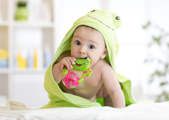Baby with green towel after the bath biting toy