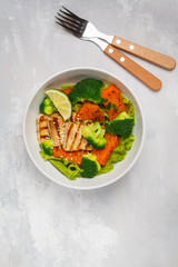 Salad with sweet potato, grilled tofu, broccoli and pecan. Healthy vegan food concept. Top view, light background, copy space.
