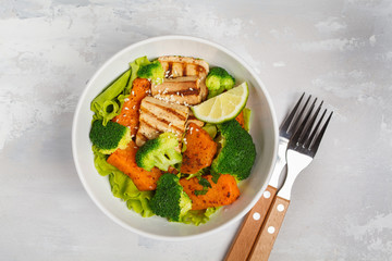 Salad with sweet potato, grilled tofu, broccoli and pecan. Healthy vegan food concept. Top view, light background, copy space.