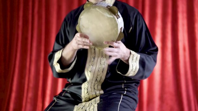 Arabic percussionist playing a decorated riq in the classical style.