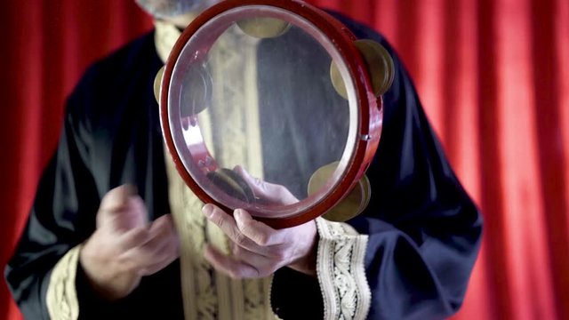 Arabic percussionist playing a the zills on a clear riq.