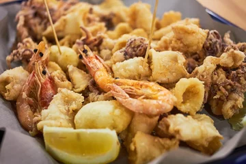 Fotobehang Een typisch Italiaans gerecht gebakken zeevruchten: garnalen, inktvis, octopus en een schijfje citroen. Italiaans fastfood. Fish and chips © lena_rx7