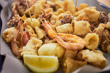 Ein typisch italienisches Gericht mit gebratenen Meeresfrüchten: Garnelen, Tintenfisch, Tintenfisch und eine Zitronenscheibe. Italienisches Fastfood. Fisch und Pommes