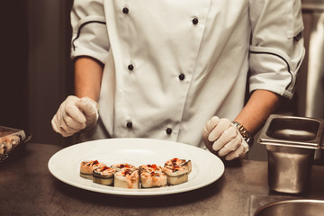 Chef is cooking set of sushi on a metal table of restaurant kitchen. Selective focus. Shallow depth of field. Toned