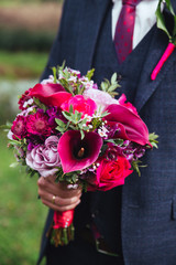 Elegant groom in costume and bow-tie with bouquet .