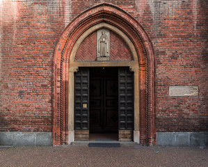brick facade with ogival portal of a fifteenth-century church of Milan, Italy