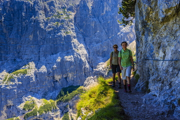 Happy family with teenager taking rest tee brake during trekking day on Dolomites mountain in summer time in Italy. Concept of travel, friendly family.