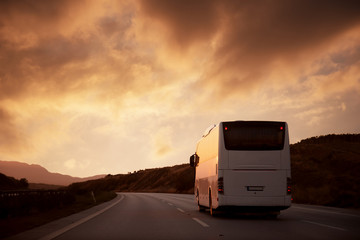 White bus driving on road towards the setting sun - 187312515