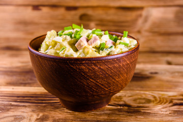 Ceramic bowl with russian traditional salad olivier on wooden table