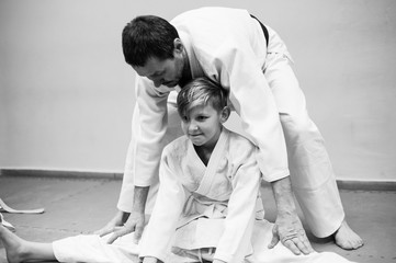 A boy in a kimono has an aikido training with a coach