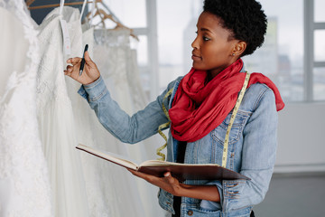Female bridal store owner looking at wedding gown