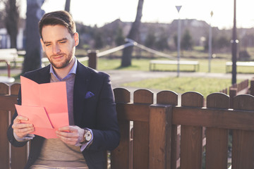 Handsome elegant man reading a love letter on Valentines Day.