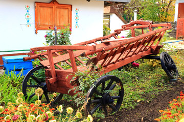 Fototapeta premium An old rural national cart with a broken wheel in the garden near the house.