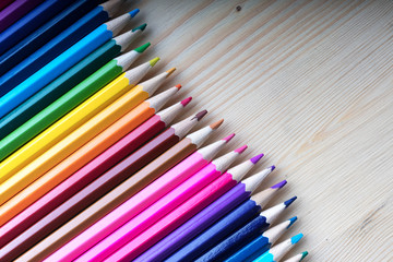 Multicolored pencils on wooden table, top view. Wooden crayons background with copyspace. School, sketching and drawing supplies.