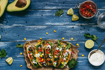 Mexican tacos with salsa and avocado on the wooden blue background, top view