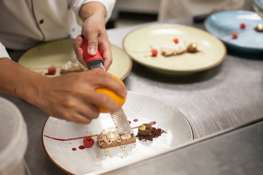 blurry background, Dessert with chef slide orange peel on top in the restaurant kitchen.