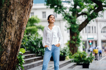 Portrait of a young Indian lady in jeans smiling in a park