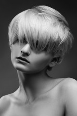 Black and white fashion beauty portrait of a blonde girl with a stylish short haircut, a fringe closes her eyes.