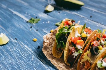 Mexican tacos with vegetables on the wooden blue background, close up.