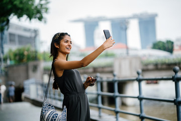 Portrait of young Indian lady taking selfie along a river