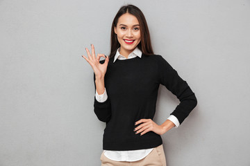 Cheerful asian woman in business clothes with arm on hip